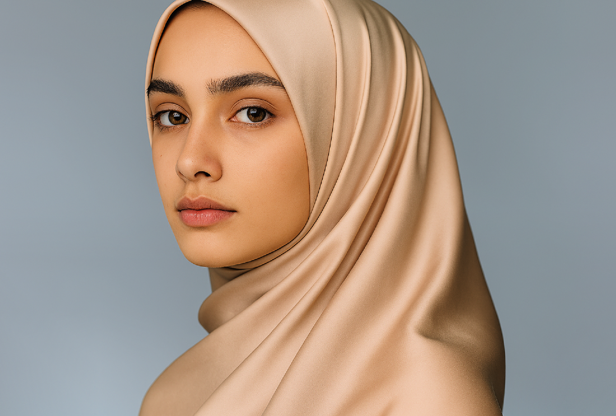 Confident Muslim woman in a champagne silk hijab with bold makeup, symbolizing high standards, self-respect, and inner strength.